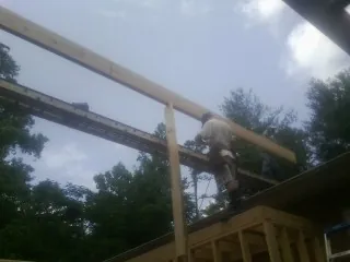 Carpenter setting a ridge beam over a new addition frame — Ice Dam Removal by Roofing Brothers in Coyote