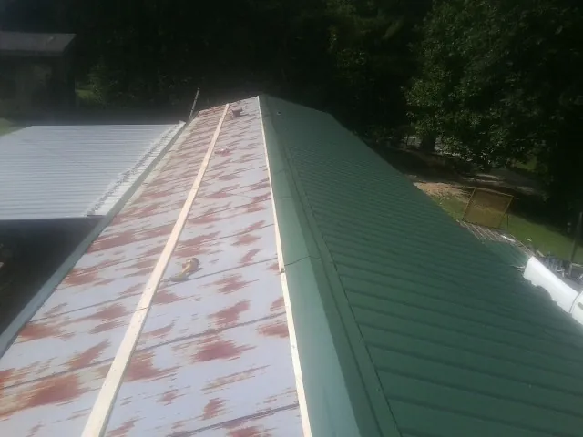 Old rusted panels beside newly installed green metal roofing — Wind Damage Roof Repair by Roofing Brothers in Coyote