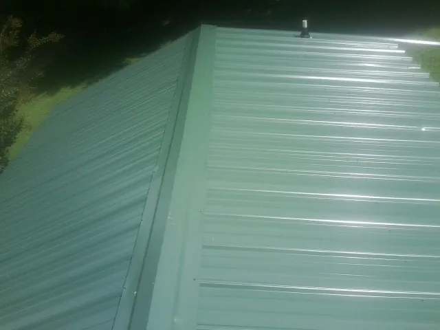 New green metal panels meeting at the ridge of a roof — Flat Roof Repair work by our crew in Coyote