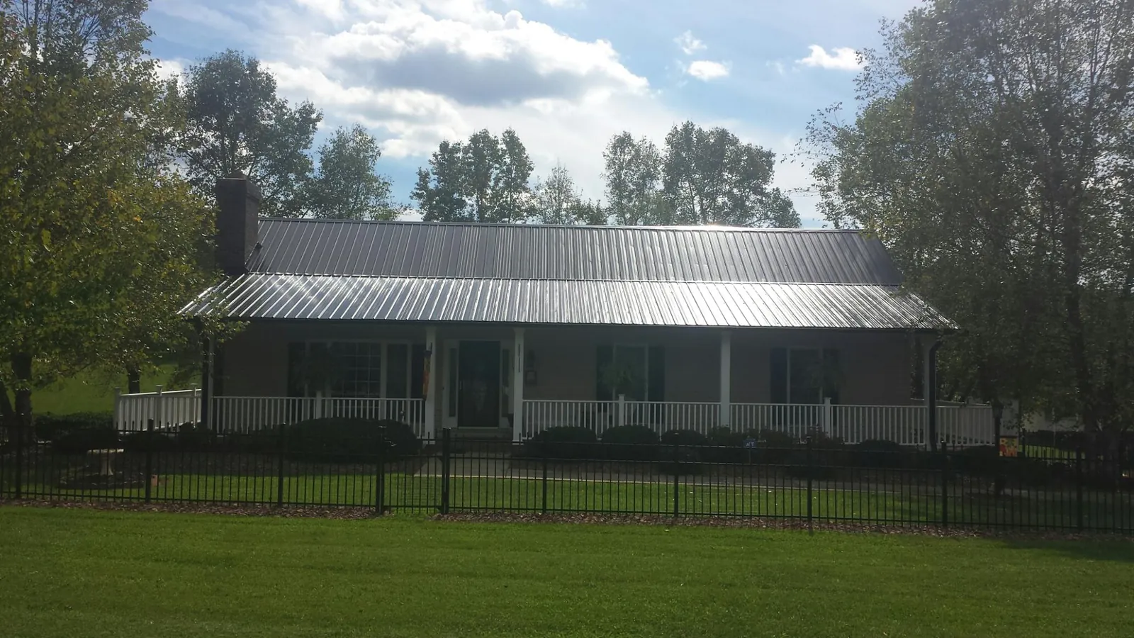 Gray metal roof on a brick ranch with a full width front porch — Gutter Guard Installation work by our crew in Coyote
